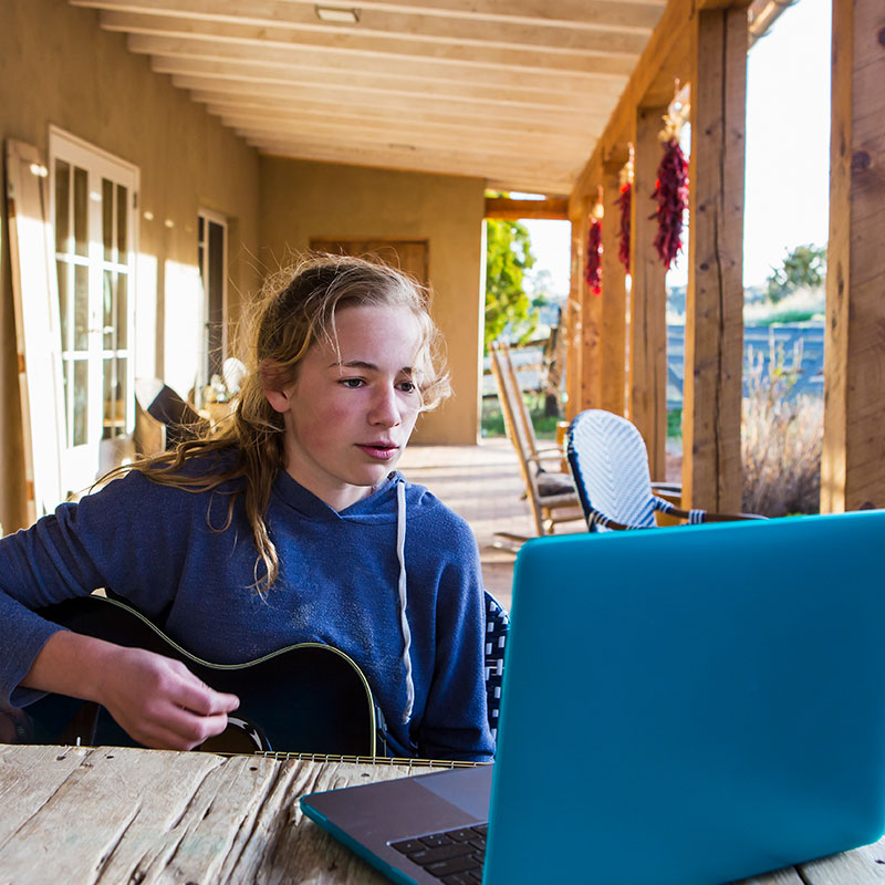 working-outside-on-computer girl on her porch studying music on the laptop